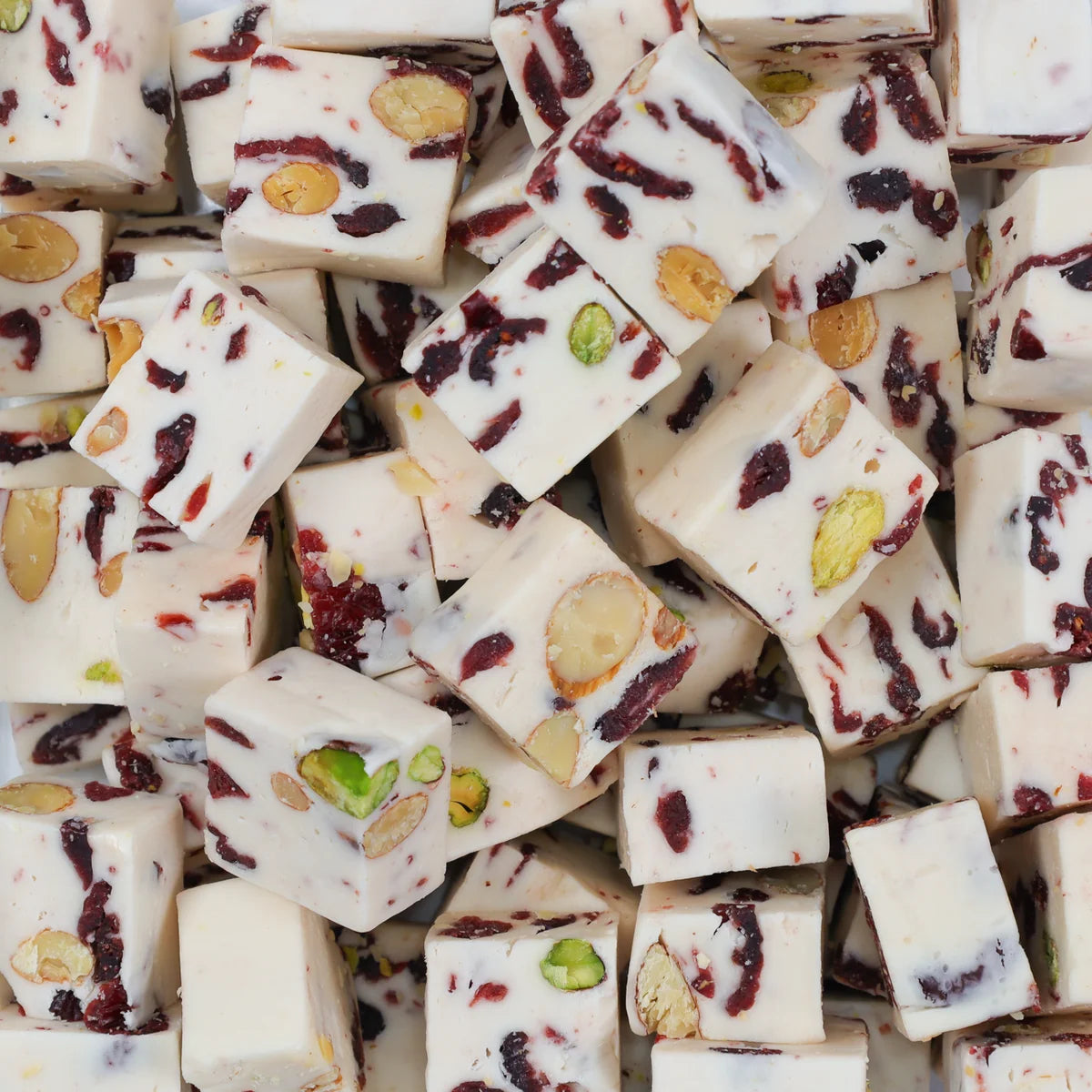 Pieces of Carousel cranberry almond pistachio nougat, white with red cranberry and green pistachio